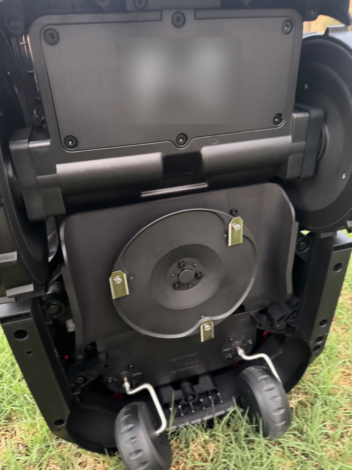 The underside of the mower showing three small razor blades on a spinning disc
